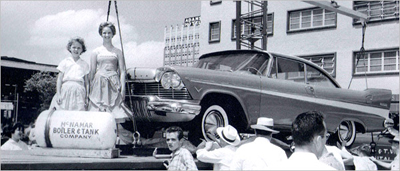 People pose for pictures as the car gets loaded