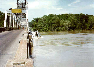 The boat is nearly submerged beneath the bridge